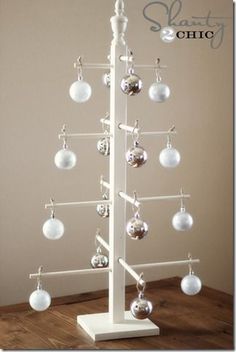 a white christmas tree with ornaments hanging from it's sides on a wooden floor