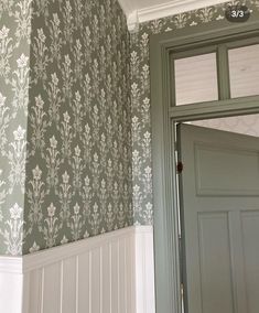 the door is open in this room with floral wallpaper