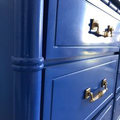 a blue dresser with brass handles and knobs