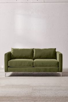 a green couch sitting in front of a white wall