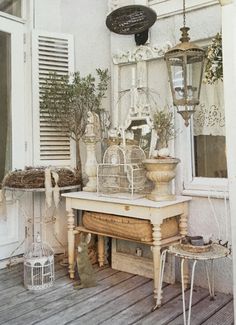 a bird cage sitting on top of a wooden table next to a lamp and window