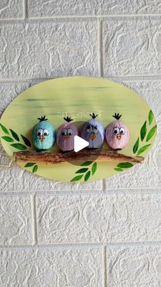 three painted birds sitting on top of a branch