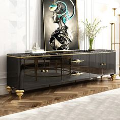 a black and gold sideboard with an art work on the wall in front of it