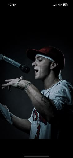 a man holding a microphone in his right hand and wearing a baseball cap on top of his head