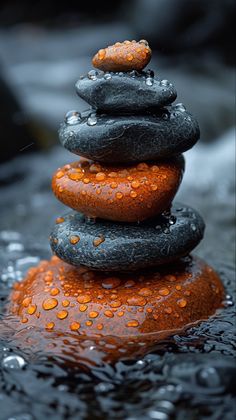 a stack of rocks sitting on top of a river covered in raindrops and water