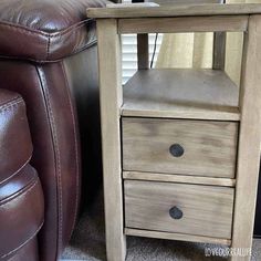 a wooden table with two drawers next to a brown leather chair in a living room