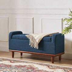 a blue bench with a blanket on top of it in front of a white wall