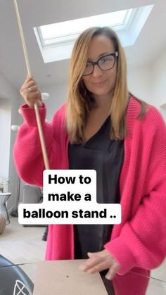 a woman standing in front of a table with a sign on it that says how to make a balloon stand