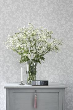 a vase filled with white flowers sitting on top of a dresser