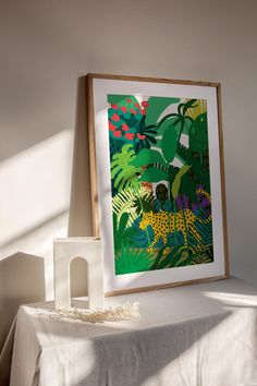 a white table topped with a painting next to a wooden frame