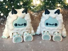 two small toy animals sitting next to each other in front of a snow covered christmas tree