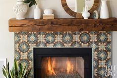 a fire place with a mirror, potted plant and vases on the mantle