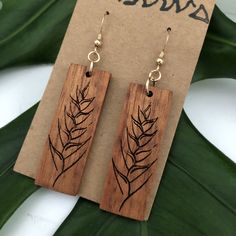 Heliconia design earring made with Hawaiian Koa Wood. These earrings are laser cut and handmade on O'ahu. Hawaiian Koa Earring is lightweight and easy to wear. The length is 6.5cm and the width is 1.5cm. The length is measured from the top of the hook. It is finished with Sterling Silver Coil Ball Earring Hooks. We repurpose the left over, discarded, or scrap koa from various woodshops and builders and use it to create our pieces. Koa is known and loved for its beautiful and complex figure, colo Woodburned Earrings, Wood Burned Gifts, Laser Engraved Earrings, Wood Jewelery, Sterling Silver Earrings Handmade, Laser Cut Jewelry, Koa Wood, Gold Filled Earrings, Wooden Earrings