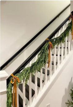 christmas garland on the banisters at the top of stairs with bows and pine cones