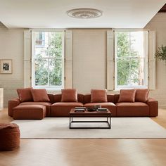 a living room filled with lots of furniture next to two large windows and a rug on the floor