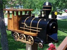 a toy train sitting on top of a wooden stand in the grass next to a tree