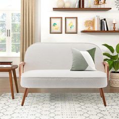 a living room with a white couch and wooden shelves on the wall next to a potted plant