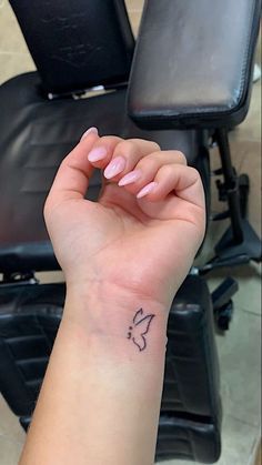 a woman's arm with a small butterfly tattoo on her left wrist, sitting in front of a chair