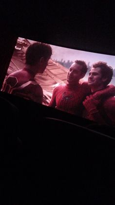 two men sitting in front of a flat screen tv with the image of spider - man on it