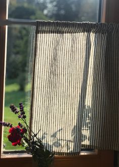 a vase filled with flowers sitting next to a window sill on top of a wooden table