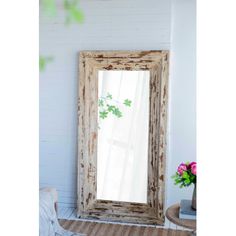 an old wooden mirror sitting on top of a table next to a vase with flowers