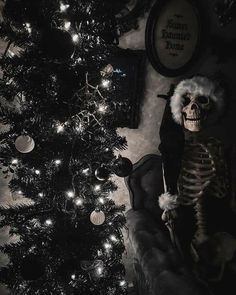 a skeleton sitting in front of a christmas tree