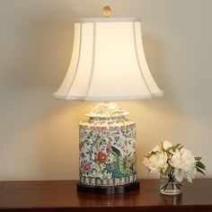 a lamp that is sitting on top of a table next to a vase with flowers