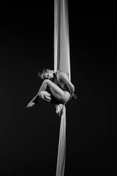 a naked woman hanging upside down on a pole