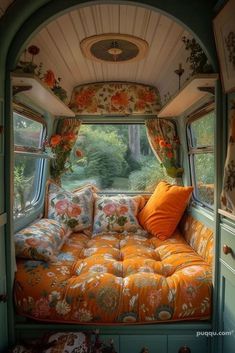 the interior of an rv is decorated with orange and green floral fabrics, pillows, and curtains