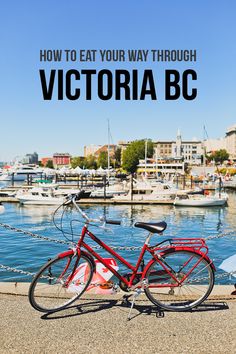 a red bike parked next to a body of water with boats docked in the background