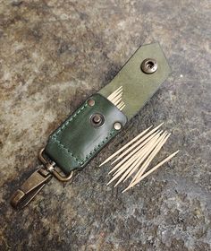 a green leather knife case sitting on top of a counter next to some wooden skewers