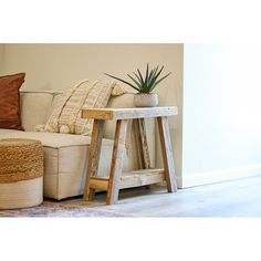 a white couch sitting next to a wooden table with a plant on top of it