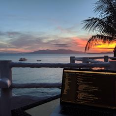 a laptop computer sitting on top of a wooden table next to a railing near the ocean