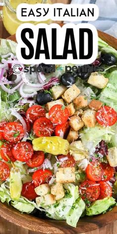 a salad with tomatoes, lettuce and croutons is shown in a wooden bowl