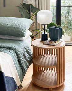 a bed room with a neatly made bed and a night stand on the side table