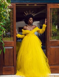 a woman in a yellow dress is standing at the entrance to a building with her hands on her hips