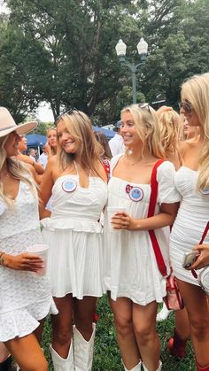 four beautiful women in white dresses and cowboy boots posing for the camera at an outdoor event