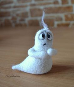 a small white stuffed animal sitting on top of a wooden table