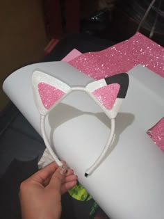 someone is making a cat ears headband out of white paper and pink sequins