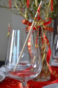 two wine glasses sitting on top of a table with red and gold ribbons around them