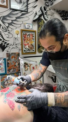 a man getting a tattoo on his arm in a room full of pictures and tattoos