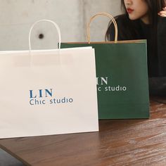 a woman sitting at a table with two bags in front of her and another bag behind her