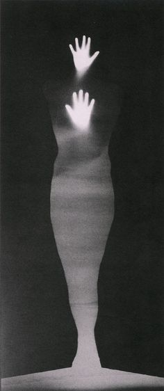 a black and white photo of a person's hand coming out of a vase