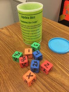 a cup sitting on top of a wooden table next to dices and a plate