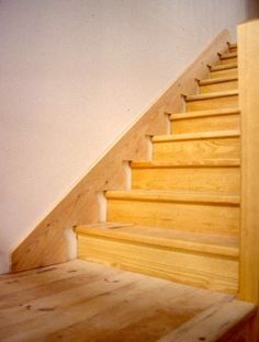 a wooden stair case next to a white wall