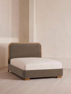 an upholstered bed frame with studded headboard and foot board in a room