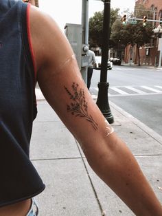 a person with a flower tattoo on their arm walking down the street next to a traffic light