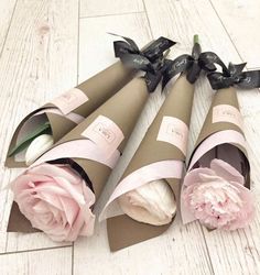 three rolled up paper flowers sitting on top of a white wooden floor next to each other