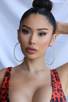 a close up of a person wearing large hoop earrings and an orange top with leopard print