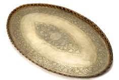 an oval metal tray with intricate designs on the bottom and sides, set against a white background